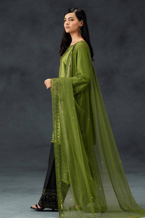 Woman wearing a green traditional outfit with a sheer dupatta against a dark background